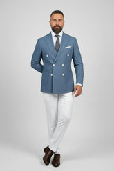 Man in midnight petrol double-breasted suit with white trousers and brown shoes.